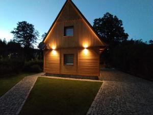 a wooden house with lights on the side of it at Sosnowa Chata - dom z prywatną sauną in Szklarska Poręba