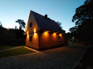 a small wooden building with lights on it at Sosnowa Chata - dom z prywatną sauną in Szklarska Poręba