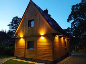 a house with lights on the side of it at Sosnowa Chata - dom z prywatną sauną in Szklarska Poręba