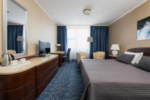 a hotel room with a bed and a television at Booking Hotel Crown Piast & Spa in Kraków