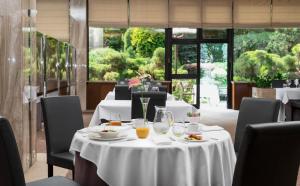 a dining room with tables and chairs with white table cloth at Booking Hotel Crown Piast & Spa in Kraków