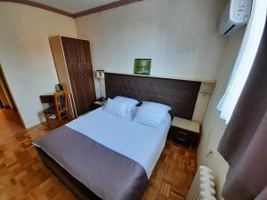 um quarto com uma grande cama branca e uma cabeceira em madeira em Hotel & Restaurant Great Wall - Airport em Saraievo