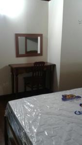 a bedroom with a table and a mirror and a bed at Cond. Hotel Âncora em frente Praia do Peró in Cabo Frio