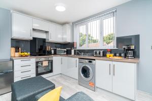 a kitchen with white cabinets and a washer and dryer at Elegant Flat Near Stonehenge, Amesbury Town Centre Smart TVs Netflix FREE PARKING in Amesbury