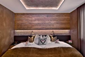 1 dormitorio con 1 cama grande y pared de madera en PETE Alpine Boutique Hotel - klein und fein - Private SPA Suiten und Zimmer, en Sankt Anton am Arlberg