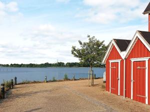 een rode schuur naast een waterlichaam bij Holiday home Gråsten LXVIII in Gråsten