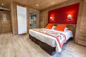 ein Schlafzimmer mit einem großen Bett mit einer roten Wand in der Unterkunft Hotel Les Bruyères in Morzine