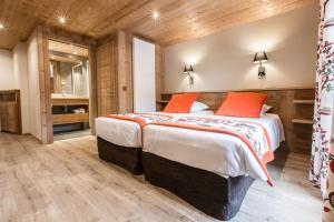 ein Schlafzimmer mit einem großen Bett mit orangefarbenen Kissen in der Unterkunft Hotel Les Bruyères in Morzine