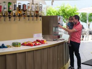 Un uomo che tiene un bambino in piedi al bancone di Hotel Leonardo Da Vinci a Limone sul Garda