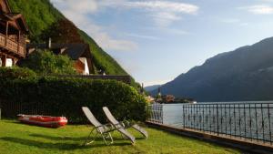 deux chaises assises sur l'herbe près d'une masse d'eau dans l'établissement Ferienwohnung KraftTanken, à Hallstatt