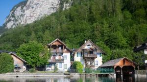 un groupe de maisons sur l'eau près d'une montagne dans l'établissement Ferienwohnung KraftTanken, à Hallstatt