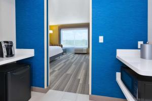 une chambre d'hôtel avec des murs bleus et un miroir dans l'établissement Holiday Inn Express & Suites - Grand Rapids Airport - South, an IHG Hotel, à Grand Rapids