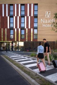 ボンデュにあるNajeti Hôtel Lille Nordの荷物を持って通りを歩く二人