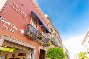 ein rosafarbenes Gebäude mit einem Balkon an der Seite in der Unterkunft Hotel Madero in Querétaro