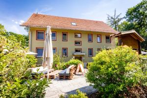 ein Haus mit einer Terrasse und einem Sonnenschirm in der Unterkunft Forsthaus Thiemsburg im Nationalpark Hainich in Schönstedt