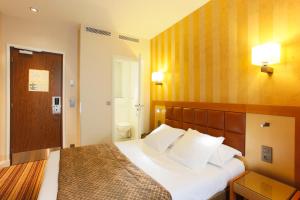 a hotel room with a bed with white pillows at Hotel Bellevue Saint-Lazare in Paris