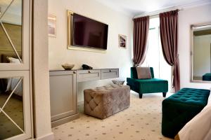 a hotel room with a television and a green chair at Villa Giardino Heritage Boutique Hotel Bol in Bol