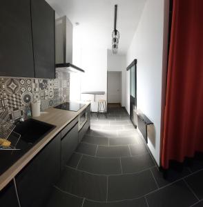 a kitchen with black cabinets and a tile floor at Les Pierres Bleues in Bar-sur-Aube