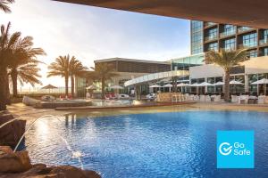 - une piscine en face d'un bâtiment avec des palmiers dans l'établissement Yas Island Rotana Abu Dhabi, à Abu Dhabi