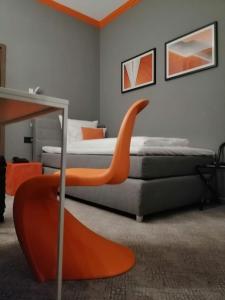 um quarto com uma cama com uma cadeira laranja em Hotel Maxplatz em Hof