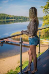 een vrouw op een balkon met uitzicht op een waterlichaam bij Apartamenty Mazurskie Klimaty (Cud Natury) in Tomaszkowo