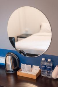 a mirror on a desk with a tea kettle and water at BEDGASM Hotel x Cafe Nimman in Chiang Mai