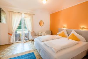 1 dormitorio con 1 cama blanca grande y pared de color naranja en Villa Konstanze, en Velden am Wörthersee