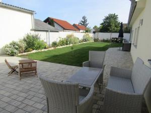 d'une terrasse avec une table, des chaises et une pelouse. dans l'établissement Peter Lamster Top1, à Frauenkirchen