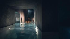 une personne dans une baignoire dans une chambre sombre dans l'établissement Le Parc Hôtel Obernai & Yonaguni Spa, à Obernai