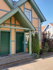 une maison avec des portes de garage vertes et une terrasse couverte dans l'établissement Ferienhaus ˋLichtblickˋ, à Rheinsberg