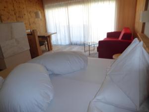 a bedroom with a white bed and a red chair at Sporthotel Rasen in Rasùn di Sotto