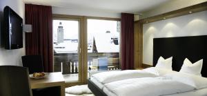 a bedroom with a large bed and a large window at Hotel Sandhof in Lech am Arlberg