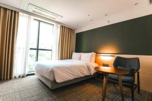 a hotel room with a bed and a table and a chair at ON City Hotel in Cheonan