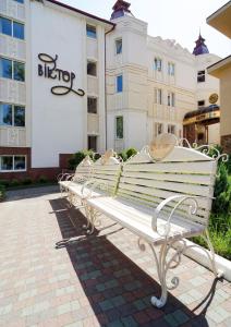 un banco blanco sentado frente a un edificio en VICTOR Hotel Resort & SPA, en Truskavets