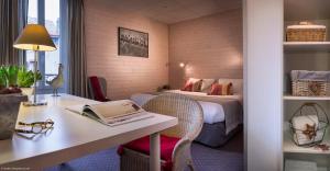 a hotel room with a bed and a desk with a book at Hôtel des Alpes in Annecy