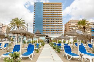 una fila di sedie e ombrelloni blu su una spiaggia di Hotel Yaramar - Adults Recommended a Fuengirola