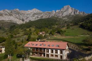 ein Haus auf einem Hügel mit Bergen im Hintergrund in der Unterkunft Apartamentos Los Picos de Europa in Colio