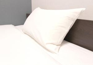 a white pillow sitting on top of a bed at Hotel Trend JR Uji Ekimae in Uji