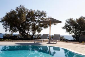 two chairs and an umbrella next to a swimming pool at Villa Beltramo Santorini 2 bedroom private pool villa in Foinikiá