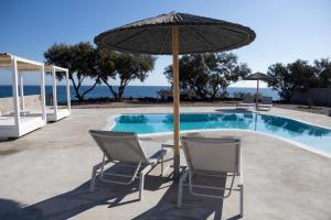 two chairs and an umbrella next to a swimming pool at Villa Beltramo Santorini 2 bedroom private pool villa in Foinikiá