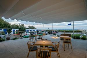 eine Terrasse mit Tischen und Stühlen sowie einen Parkplatz in der Unterkunft Apartamentos Marfina in Castelldefels