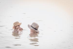 two babies wearing hats sitting in the water at Mauricia Beachcomber Resort & Spa in Grand Baie