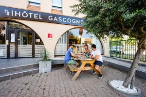 three men sitting at a picnic table in front of a store at Hotel Gascogne in Toulouse