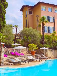 - une piscine avec des chaises et des parasols en face d'un bâtiment dans l'établissement Villa Miravalle, à Riva del Garda