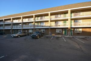 an apartment building with cars parked in a parking lot at HomeTowne Studios by Red Roof Denver - Lakewood West in Lakewood