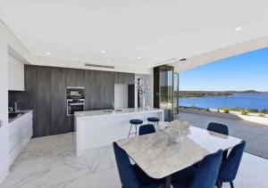 eine Küche mit einem Esstisch und Blick auf das Wasser in der Unterkunft Stylish Penthouse with Views & Jacuzzi in Gosford