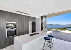 eine Küche mit einer Theke mit Stühlen und Meerblick in der Unterkunft Stylish Penthouse with Views & Jacuzzi in Gosford