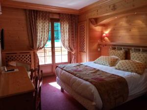 a bedroom with a bed and a table and a window at Hotel les Sapins in La Clusaz