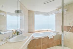 a bathroom with a tub and a sink and a window at Hotel Seagull Tenpozan Osaka in Osaka