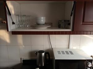 um micro-ondas numa cozinha com pratos e copos em Semuya Apartments em Ndola